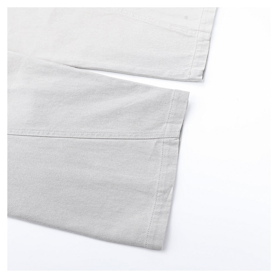 Close-up of the straight hems and stitched seams on the light gray trouser legs.