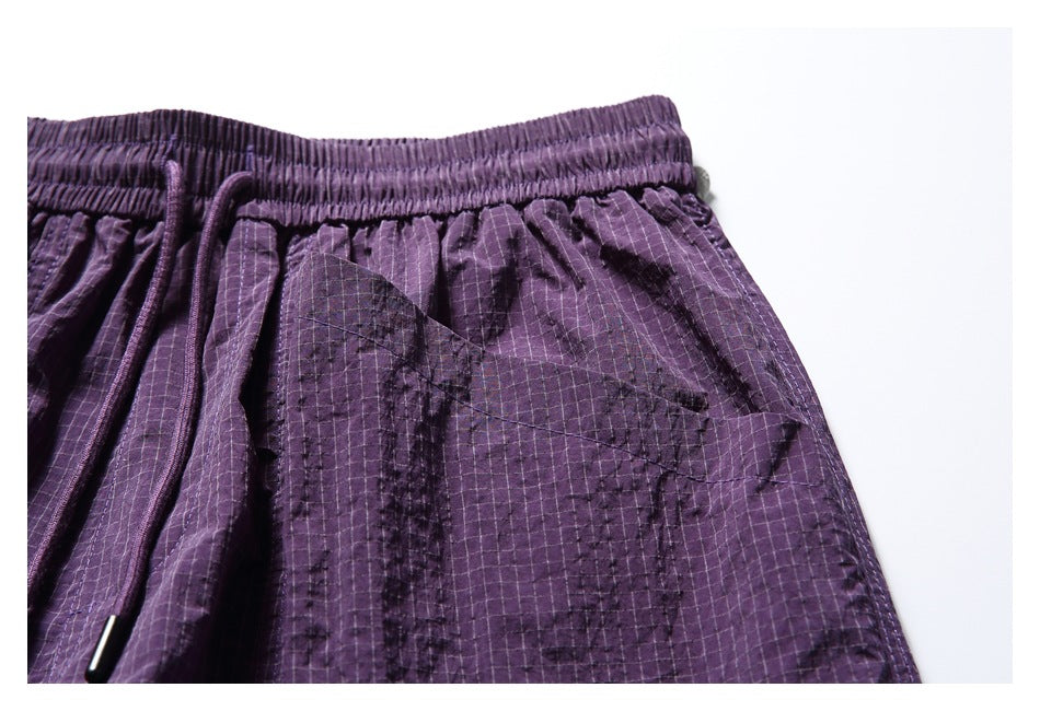 Close-up of the purple shorts' elastic waistband, drawstring and upper front pocket area.