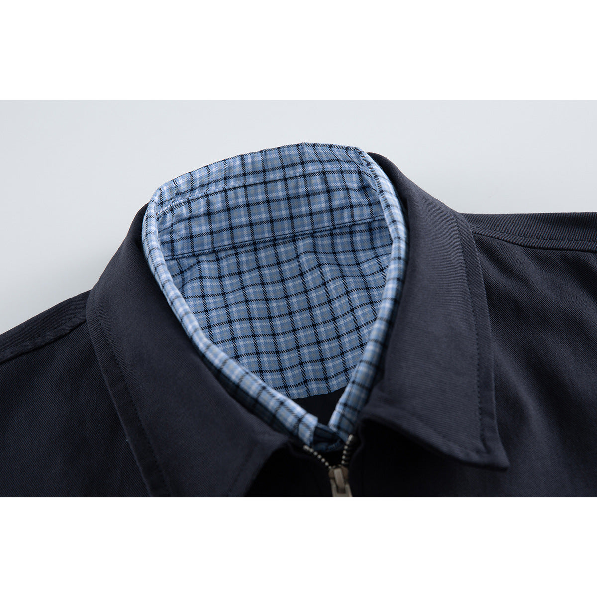 Close-up of a dark navy jacket collar and zipper, showing light blue plaid lining.