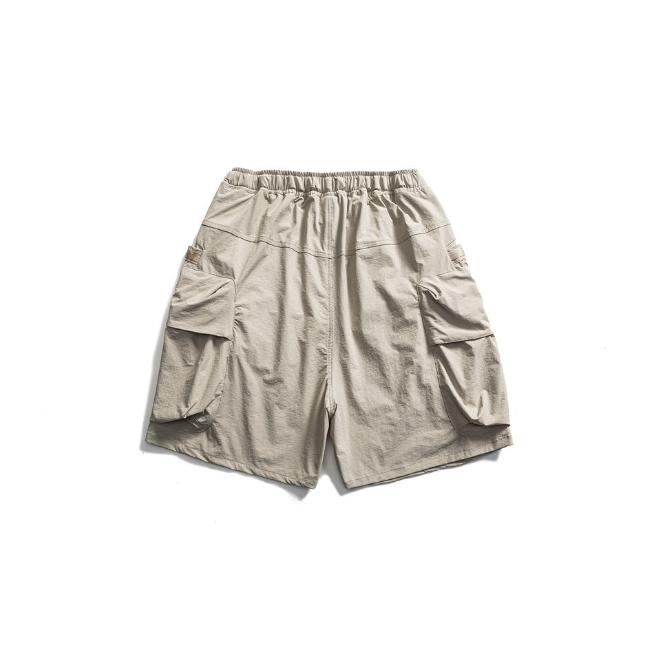 Back view of light gray cargo shorts with an elastic waistband and large flap pockets on both legs.