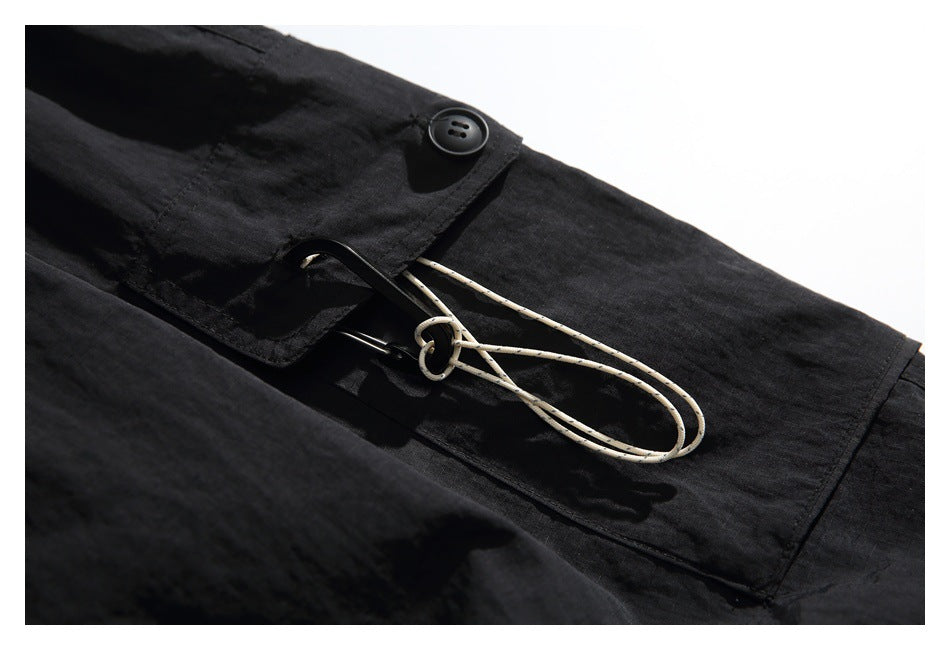 Close-up of a black buttoned flap pocket with a light-colored loop cord on black pants.