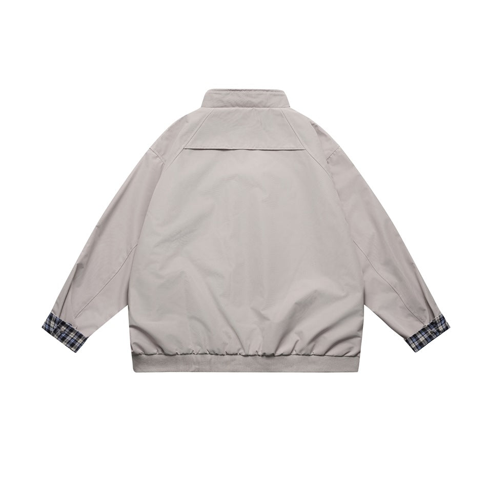 Back view of a light gray jacket with a stand collar, shoulder yoke, ribbed hem, and plaid sleeve cuffs.