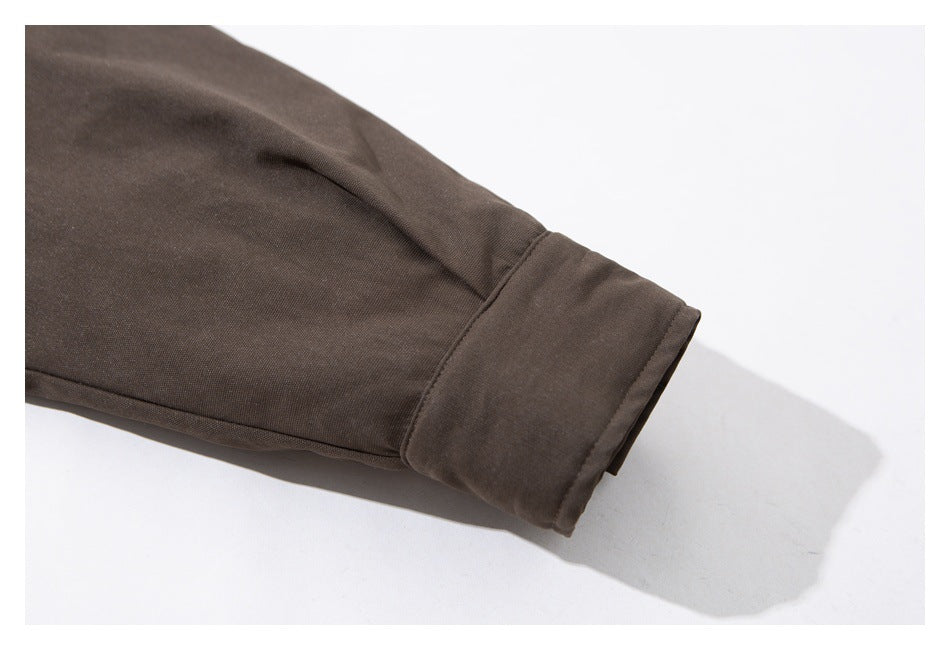Close-up of a dark brown coat sleeve ending in a wide cuff.