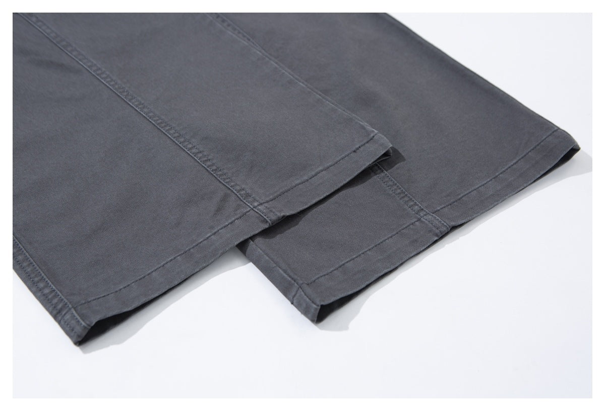 Close-up of charcoal trouser legs showing straight stitched hems and panel seams.