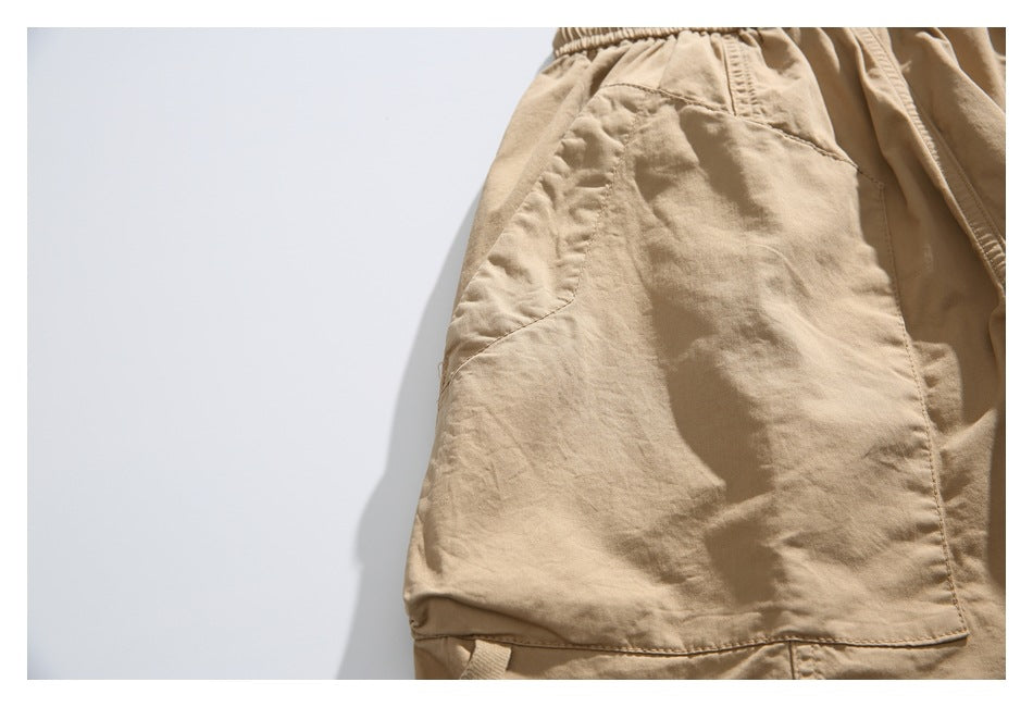 Close-up of the tan shorts’ side pocket and stitched leg panel.