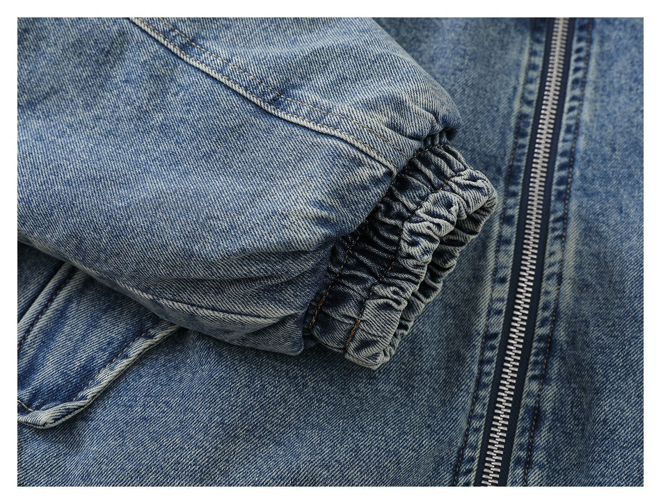 Close-up of a blue denim sleeve with a gathered elastic cuff beside the jacket zipper.