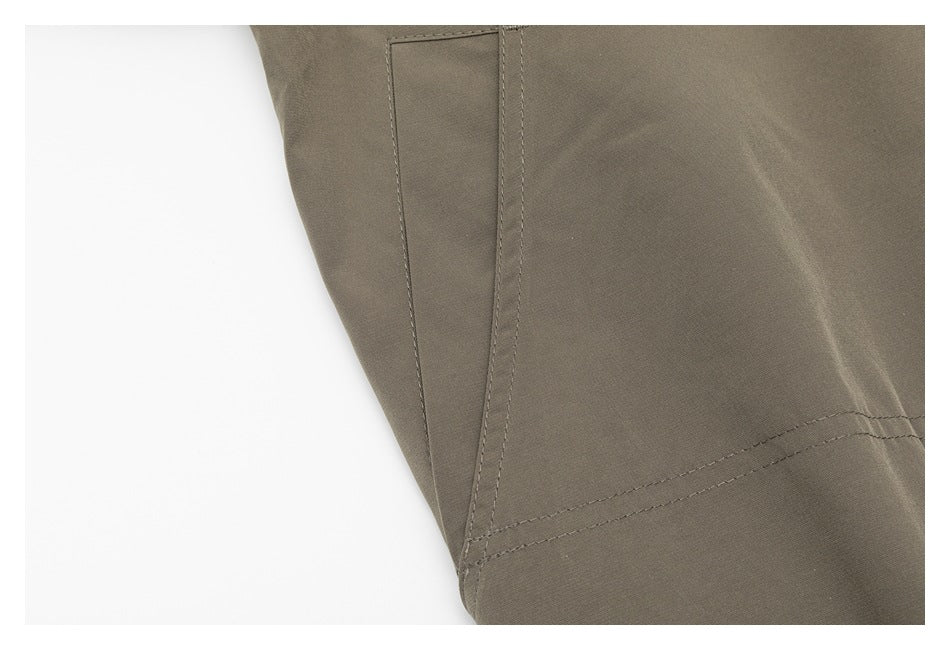 Close-up of a taupe jacket side panel with stitched seams.