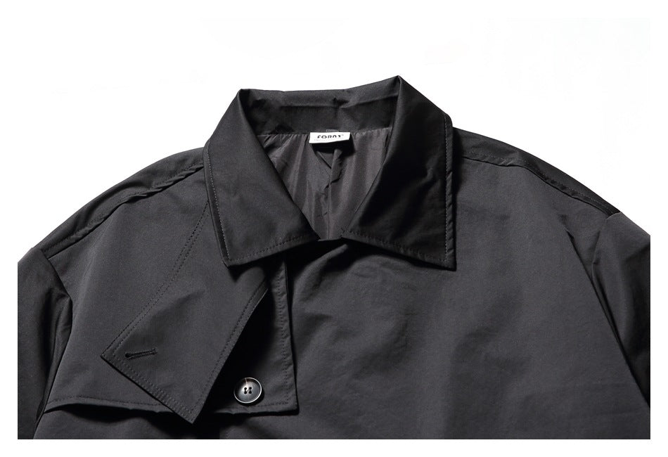 Close-up of the black coat’s pointed collar, front fastening, and small sewn-in neck label.