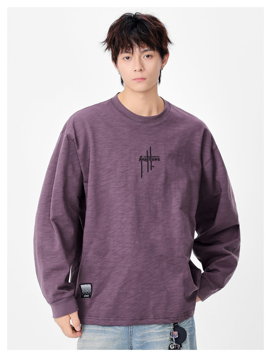 Front view of a model wearing an oversized plum long-sleeve shirt with a small black chest graphic.
