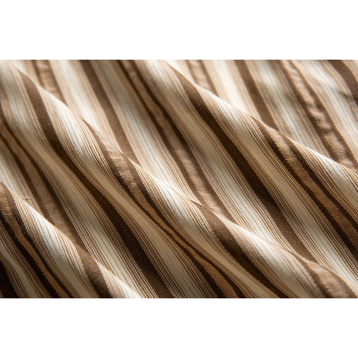 Macro view of the cream, tan, and brown striped shirt fabric and its fine woven texture.