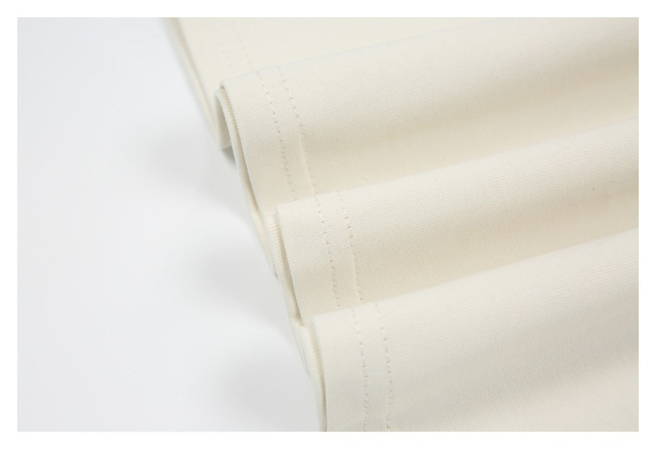 Close-up of an ivory garment edge with parallel rows of stitching and folded fabric.