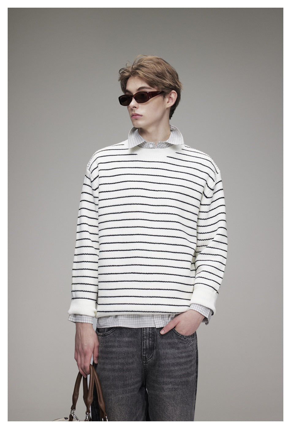 Close-up of model wearing white sweater with black stripes over a checked collared shirt