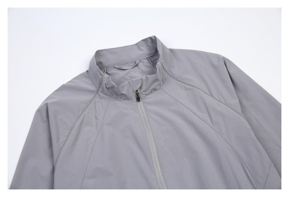 Close-up of the light gray jacket's front, showing the stand collar, center zipper, and curved shoulder seams.