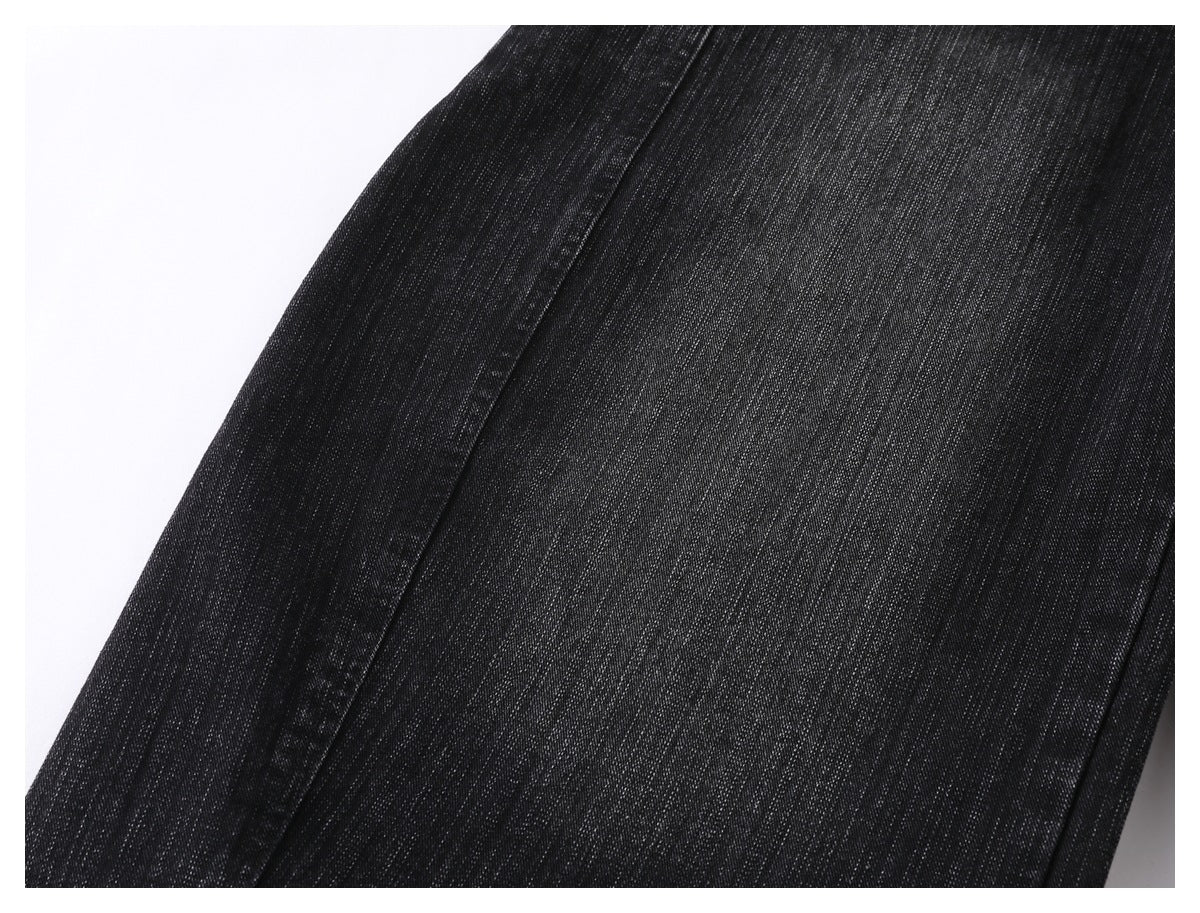 Close-up of black jeans fabric showing subtle gray vertical texture and a stitched seam.