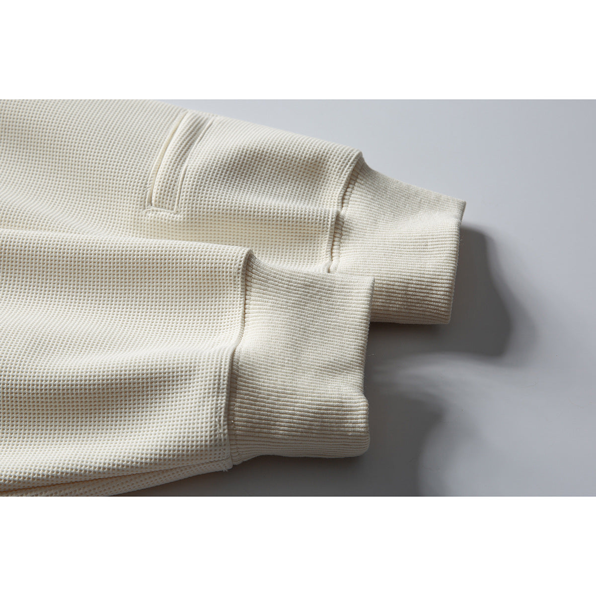 Close-up of the ivory waffle-knit sweatshirt sleeves and wide ribbed cuffs.