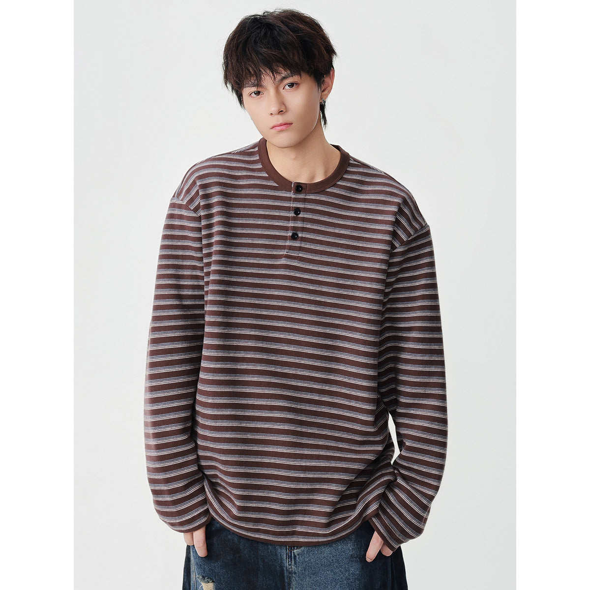 Model wearing a brown and gray striped long-sleeve henley with a brown neckline and three-button placket.