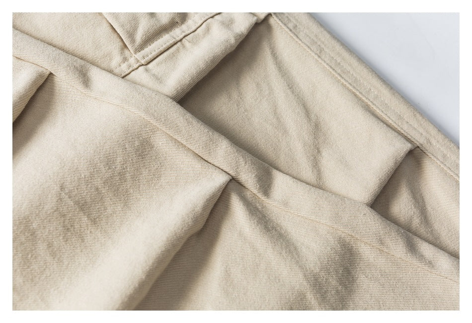 Close-up of beige trouser fabric with overlapping stitched seams.