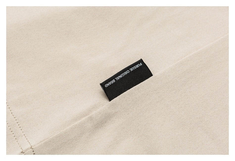 Close-up of beige garment fabric with a black sewn-in label reading “PURE ORIGINAL BRAND.”