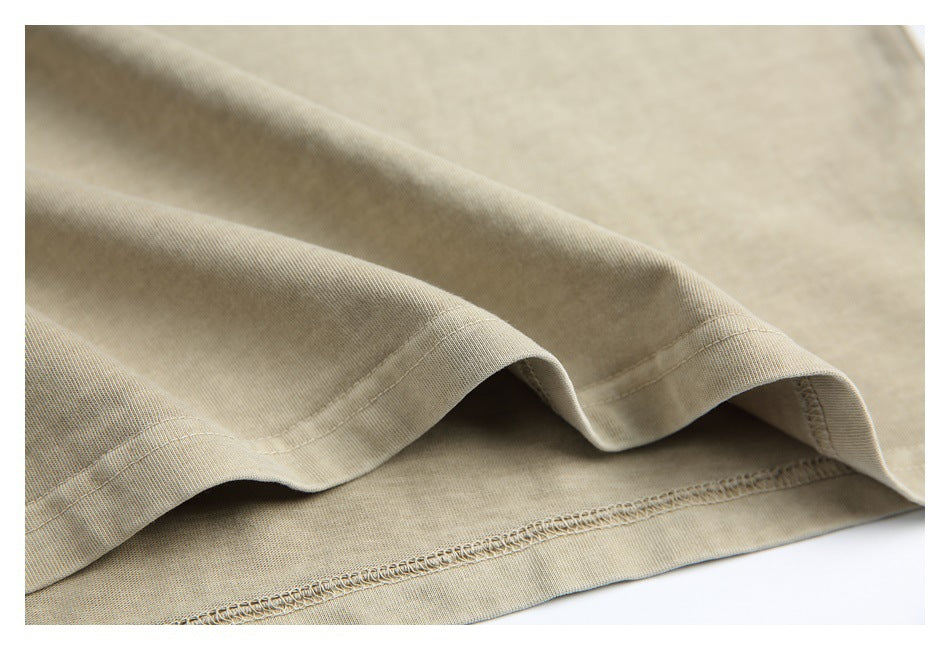 Close-up of beige fabric showing a folded hem with visible stitching and an overlocked edge.