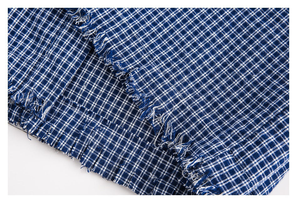Close-up of navy and white checked fabric showing frayed seams and edges.