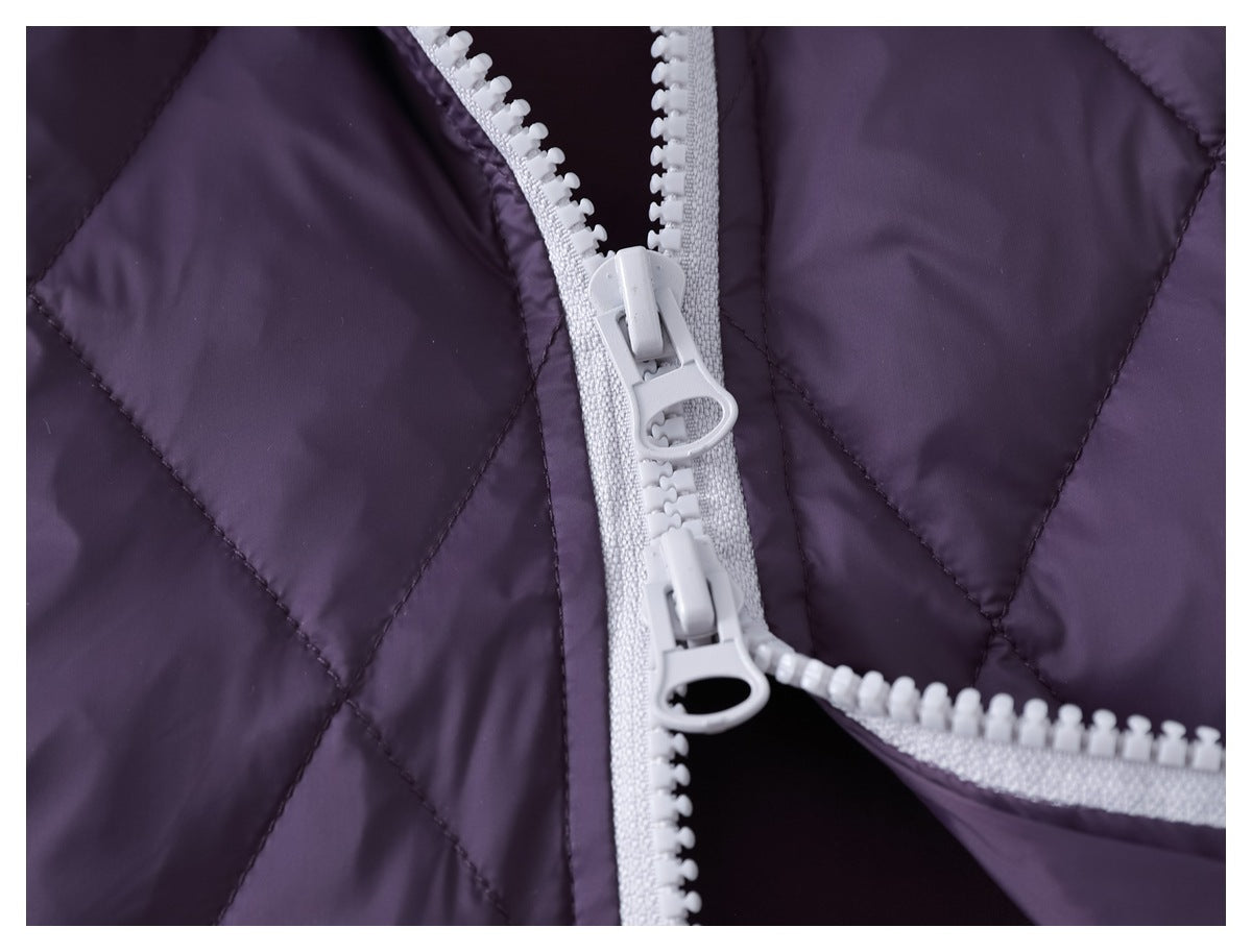 Close-up of an opened light gray two-way zipper on a dark purple quilted garment.