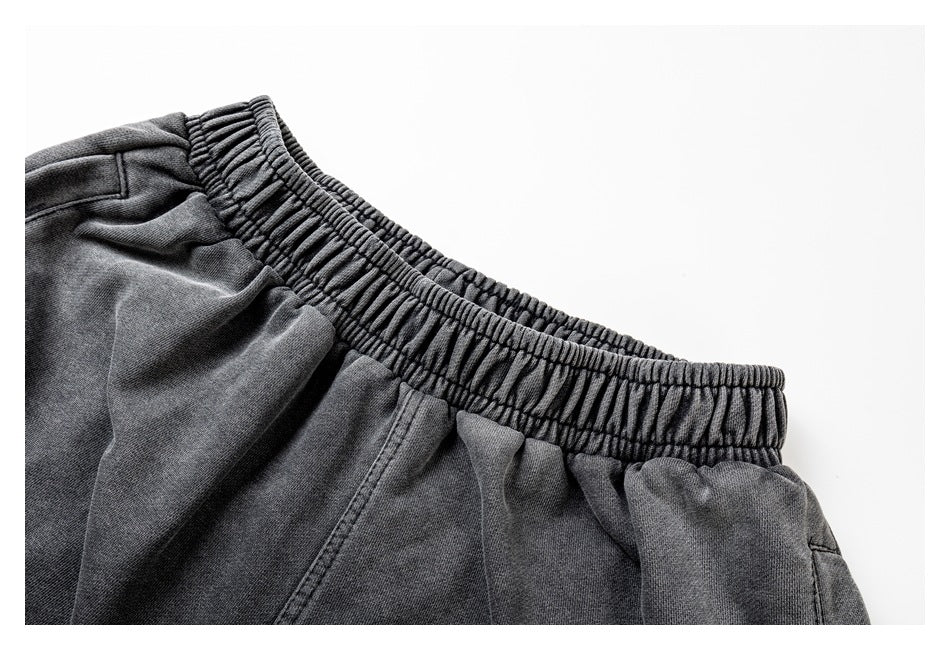 Close-up of charcoal-gray pants showing the gathered elastic waistband and upper fabric.