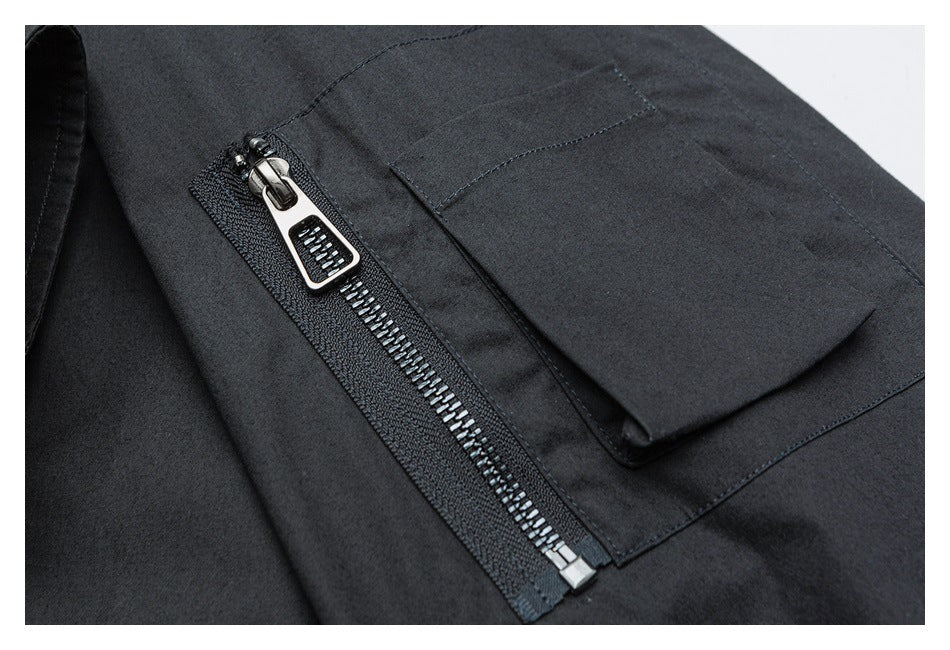 Close-up of a dark garment with a shiny metal zipper beside a flap pocket.
