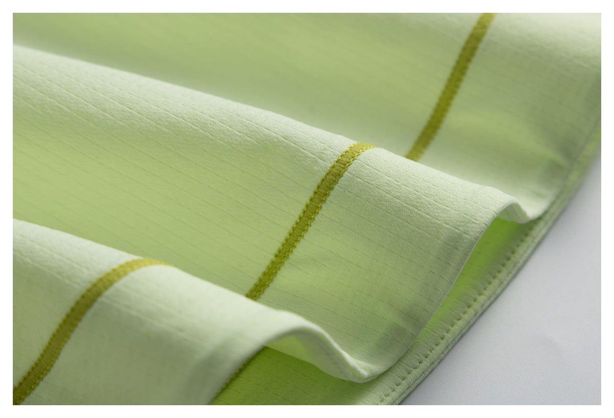 Close-up of a pale lime garment hem with yellow-green stitching and seam details.