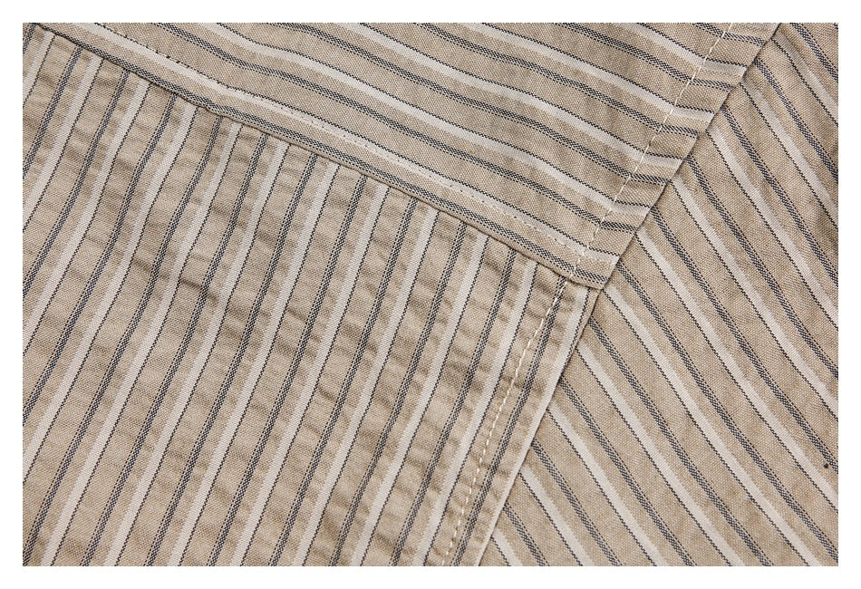 Close-up of beige striped fabric showing an overlapping seam and parallel topstitching.