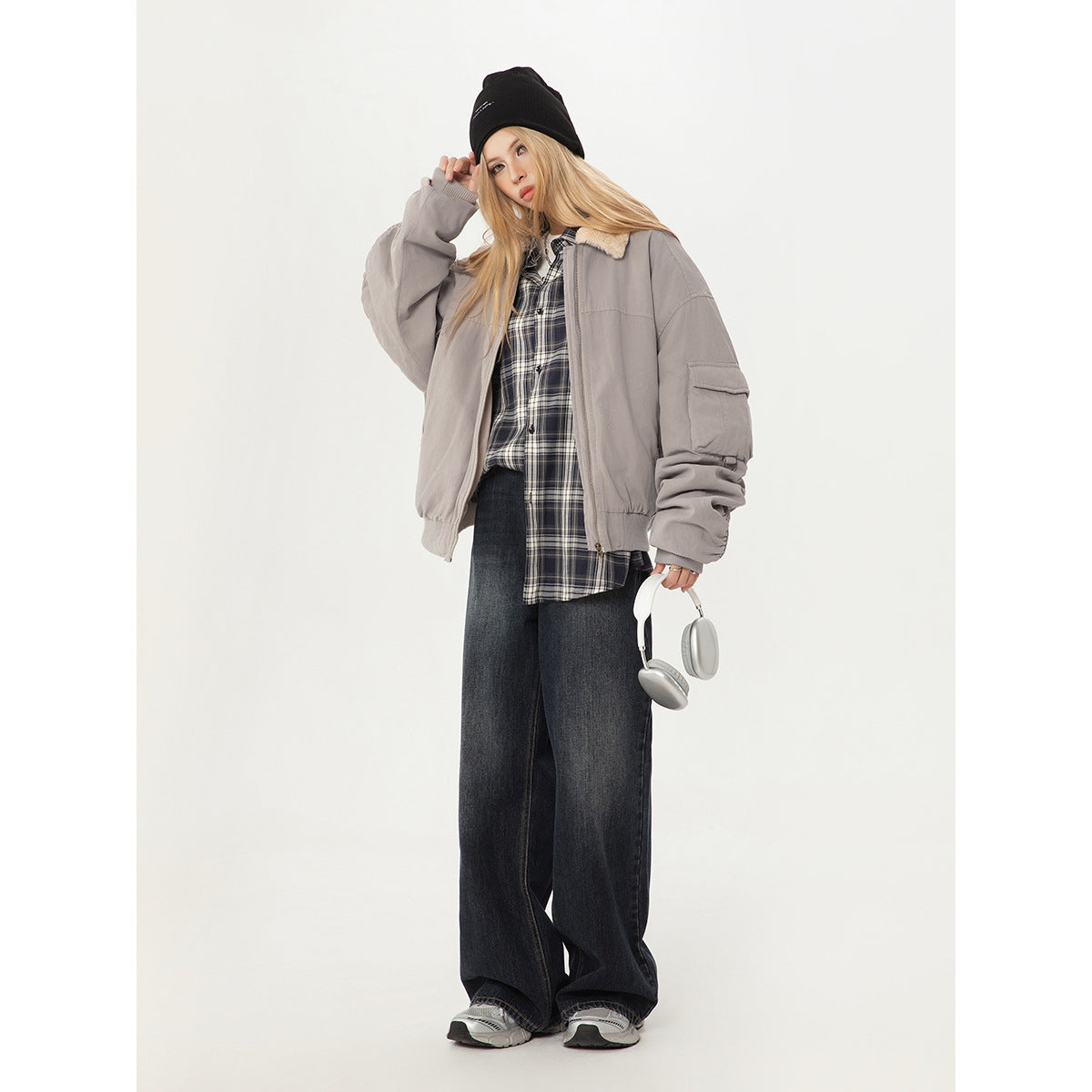 Model wearing a light gray shearling-collar bomber jacket with a plaid shirt and wide-leg dark jeans.