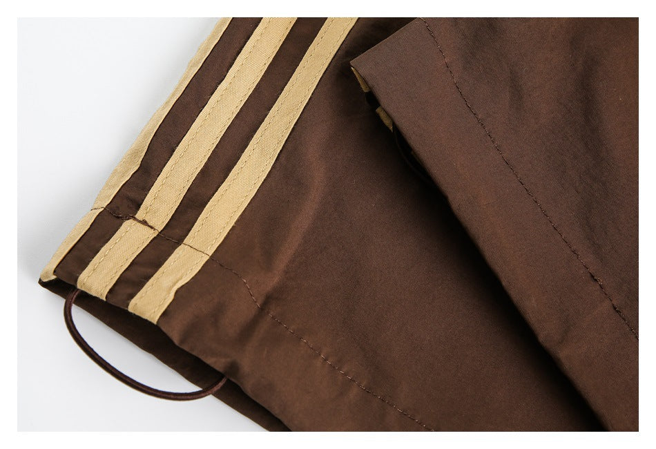 Close-up of the brown pant leg hem with tan side stripes and a looped drawcord.