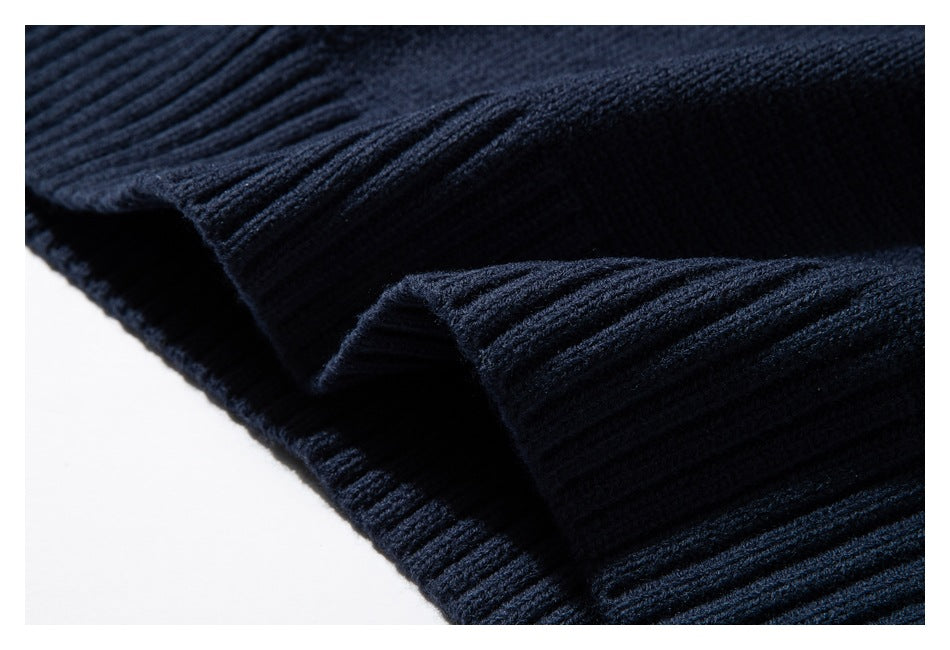 Close-up of the dark navy sweater's ribbed knit edge and folded fabric.