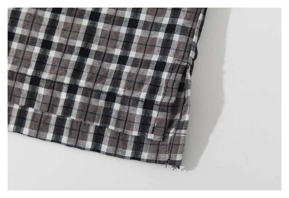 Close-up of the plaid shirt's lower hem and side seam against a white background.