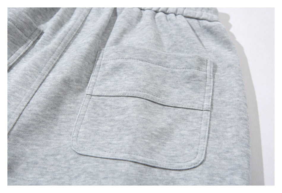 Close-up of light gray sweatpants showing a rear patch pocket and elastic waistband.