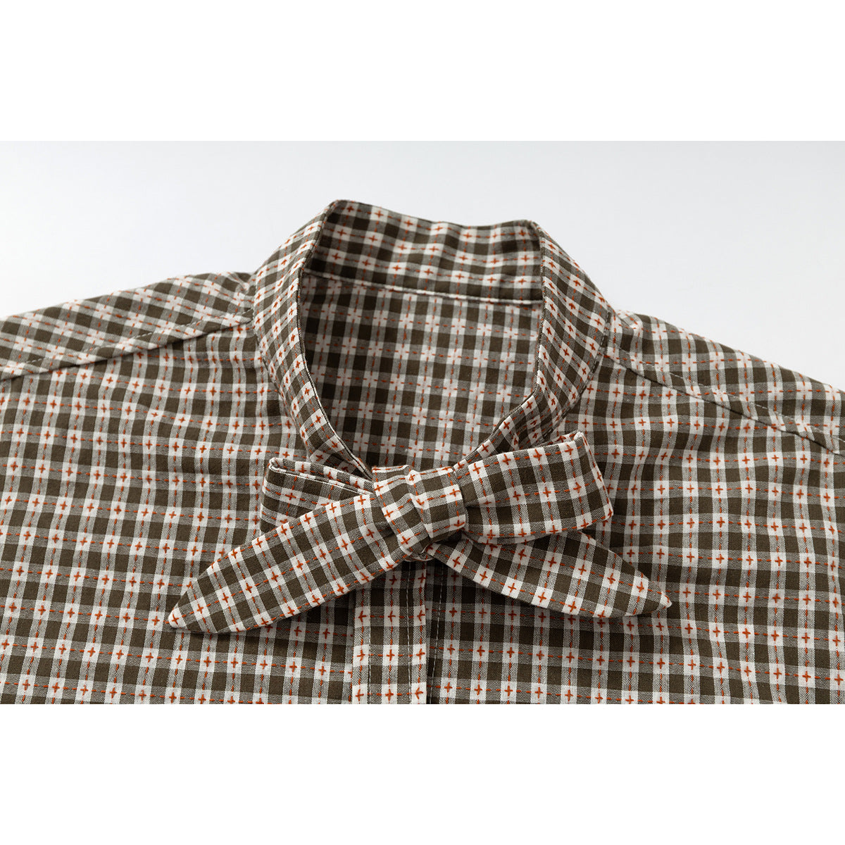 Close-up of a brown, white, and rust plaid shirt collar with a matching bow tie.