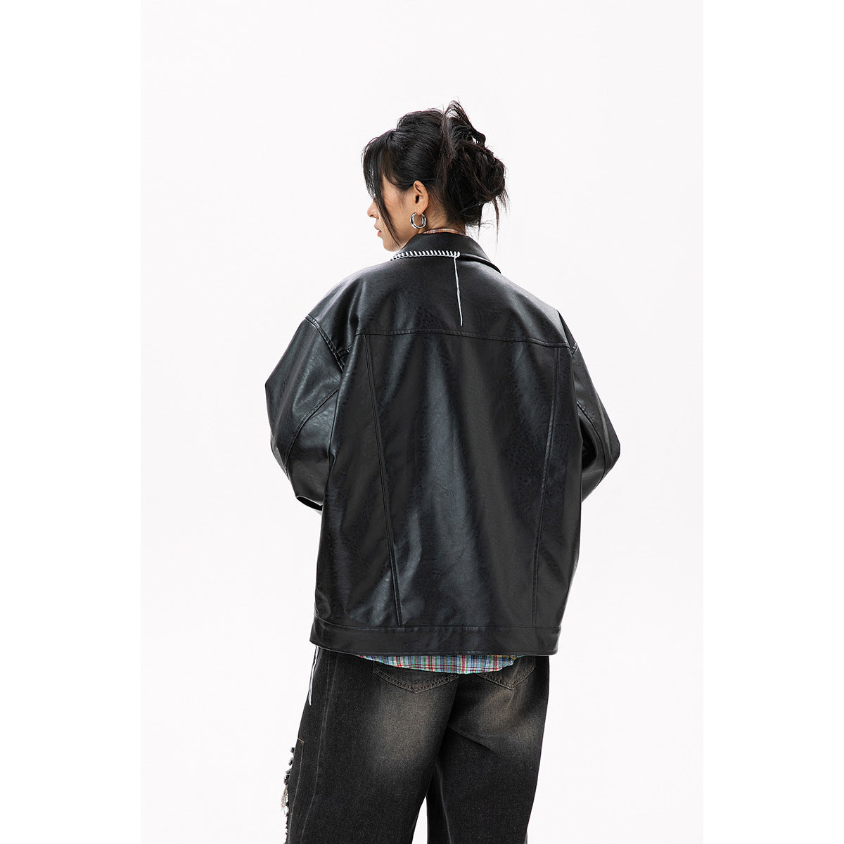 Rear view of a model wearing an oversized black jacket with white stitch detail across the collar.