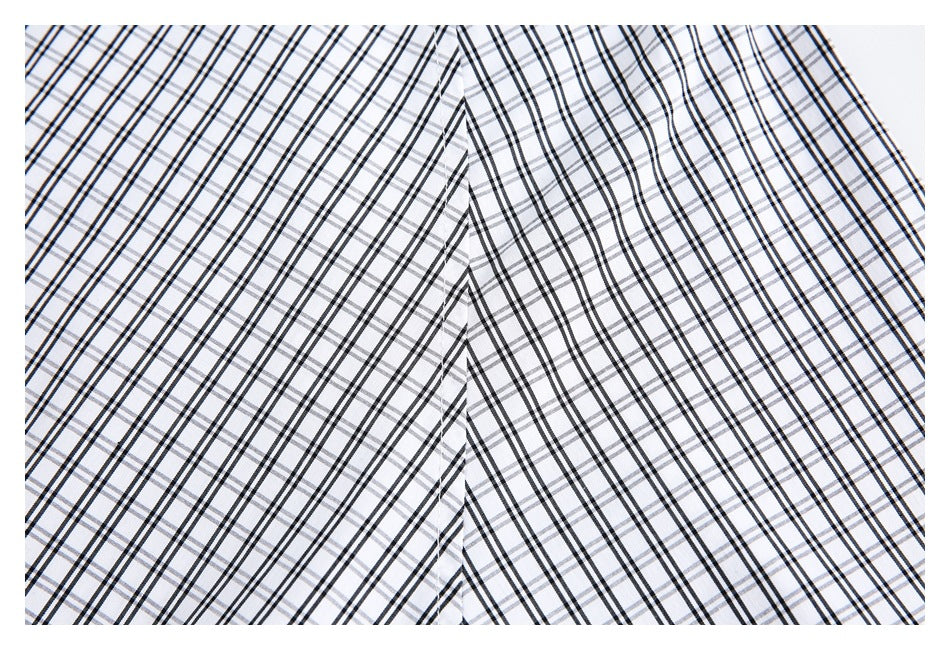 Close-up of white fabric with a black and gray plaid pattern and a stitched seam.