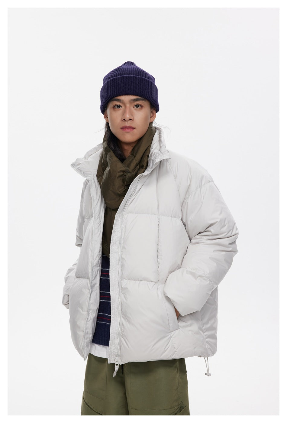 Closer view of a model wearing an open white quilted puffer jacket with a raised hood and layered outfit.