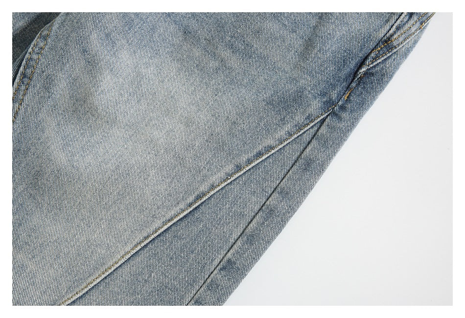 Close-up of washed blue denim with a diagonal stitched seam.