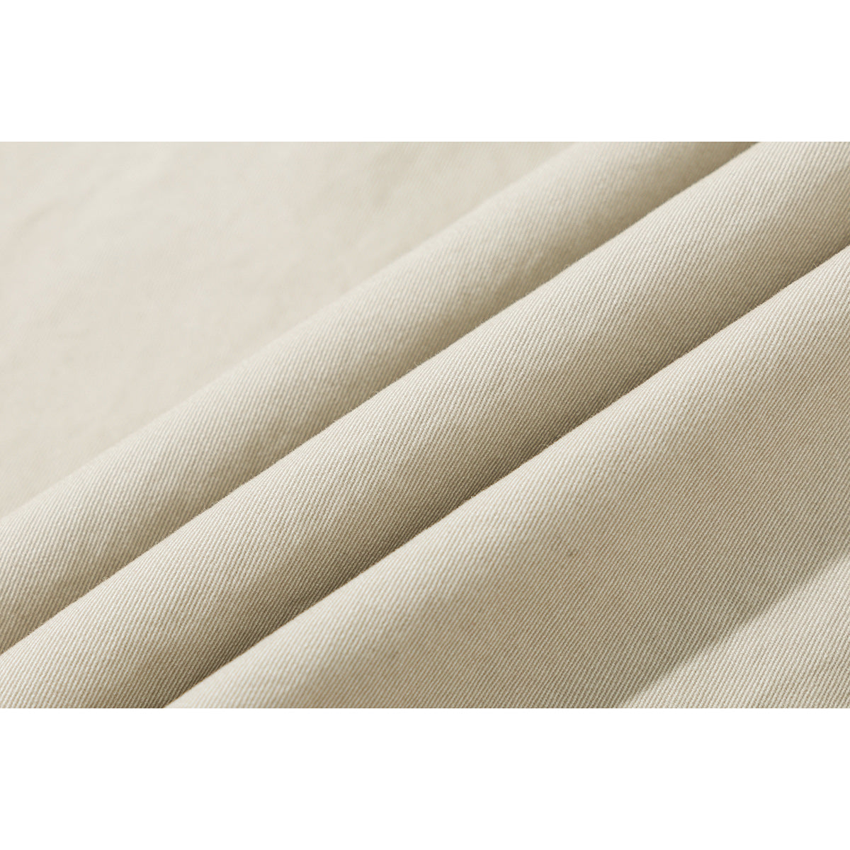 Macro view of the fine diagonal weave and folds of light beige shirt fabric.