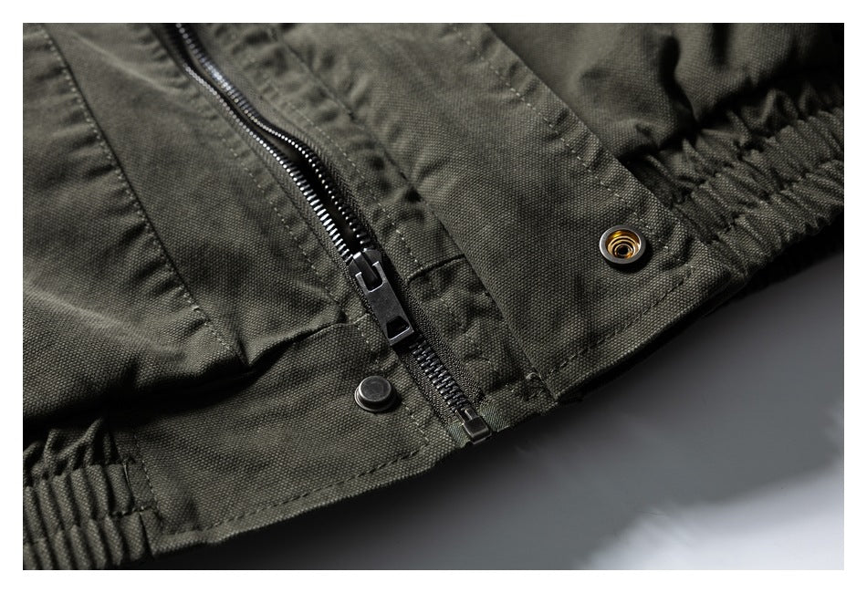Close-up of an olive drab jacket’s front zipper, snap fasteners and gathered hem.