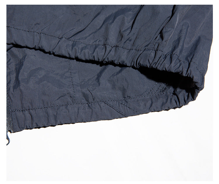 Close-up of the navy jacket's gathered elastic hem and stitching.