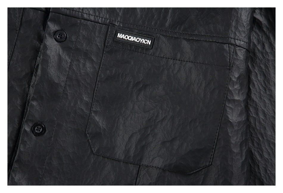 Close-up of a black textured shirt’s button placket and large chest pocket with a small label.