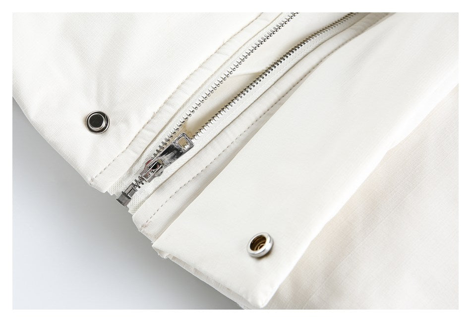 Close-up of a silver zipper and round metal snaps on a white garment.