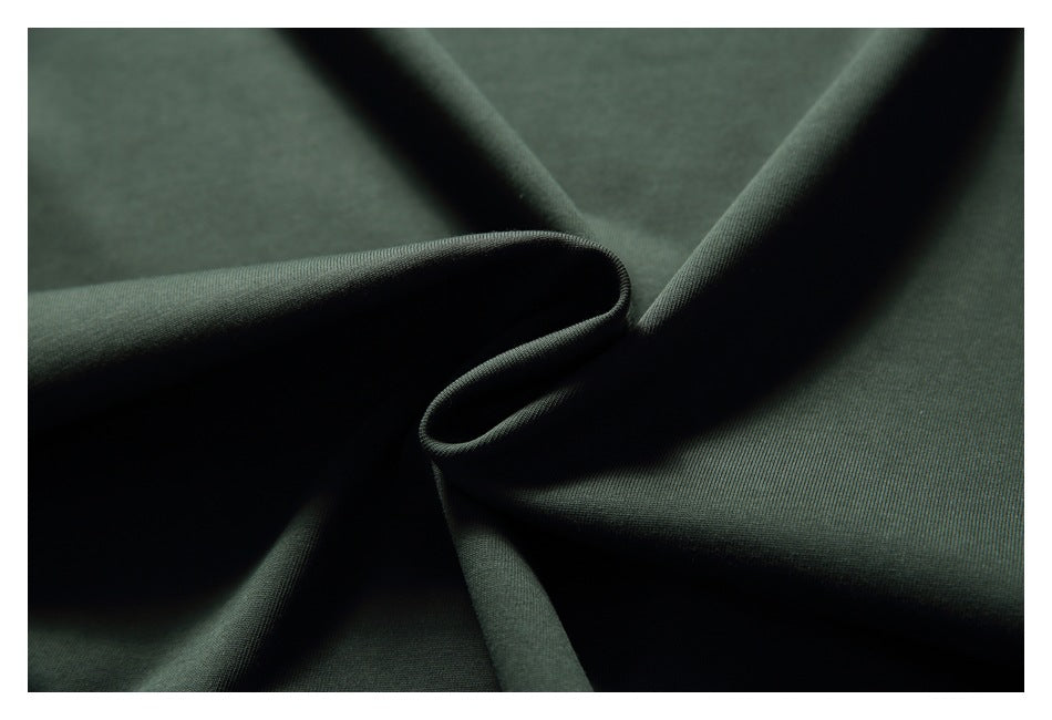 Close-up of dark green fabric arranged in soft folds, showing its fine textured surface.