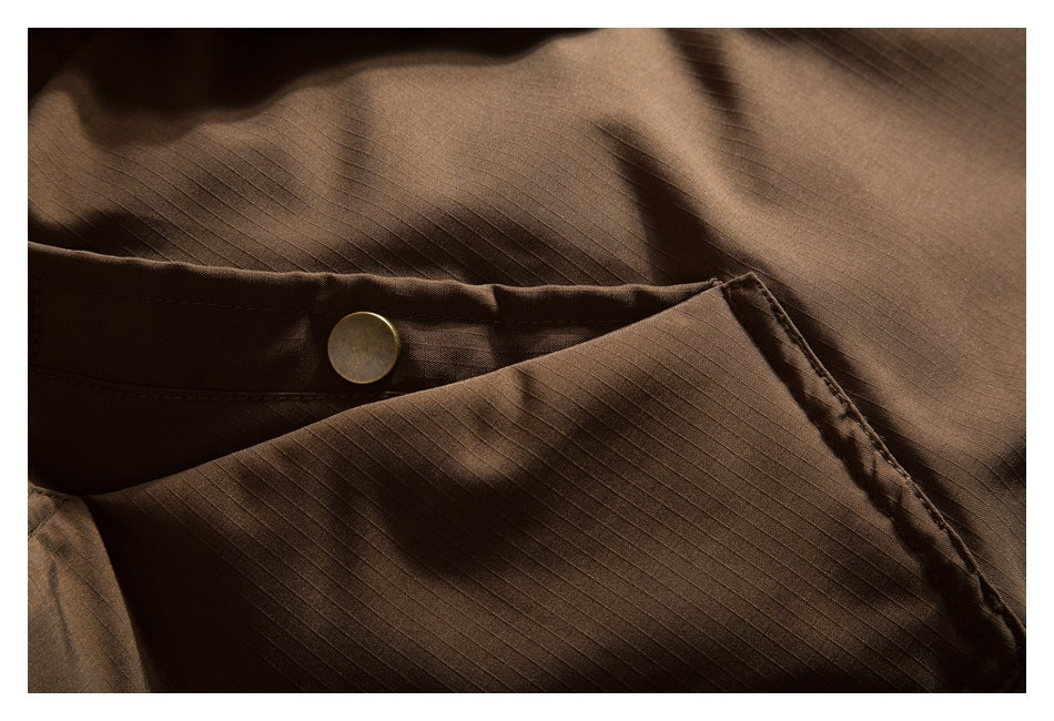 Close-up of brown garment fabric with fine grid texture, stitching, and a round brass-tone button.
