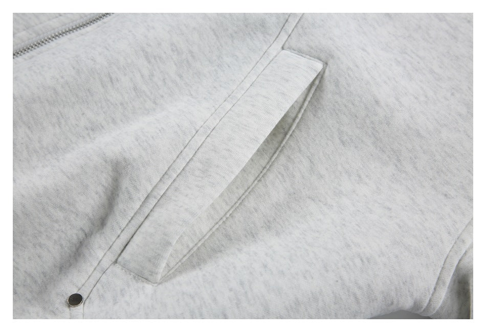 Close-up of a slanted welt pocket on a light gray marled jacket, with a small dark snap at the edge.
