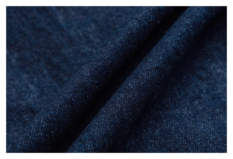 Macro view of dark indigo denim fabric gathered into soft folds.