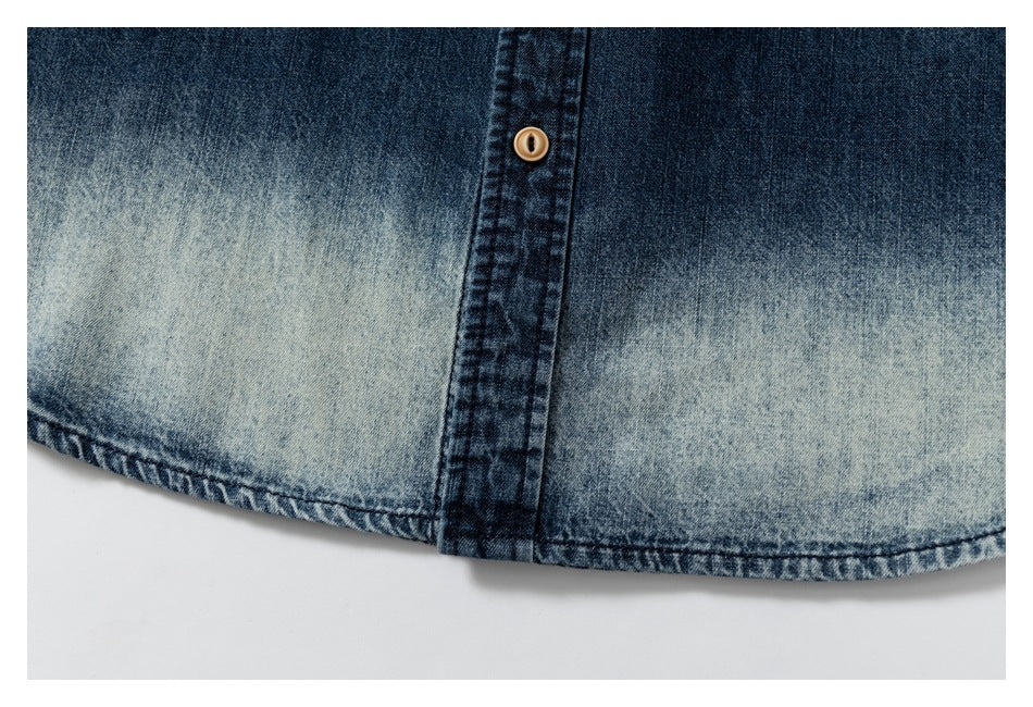 Close-up of faded blue denim with a dark button placket and stitched lower hem.