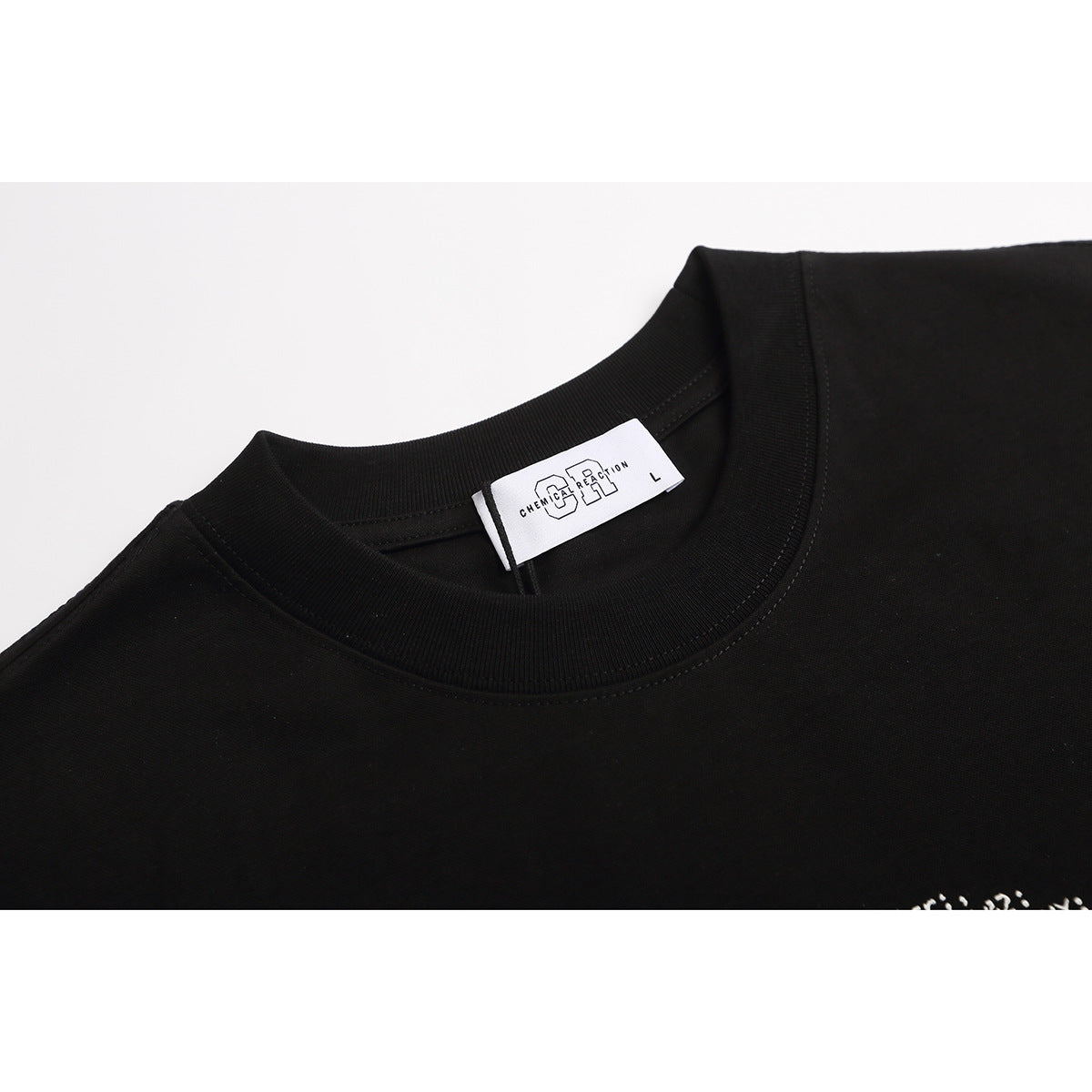 Close-up of a black T-shirt's ribbed crew neck and sewn white Chemical Reaction size label.